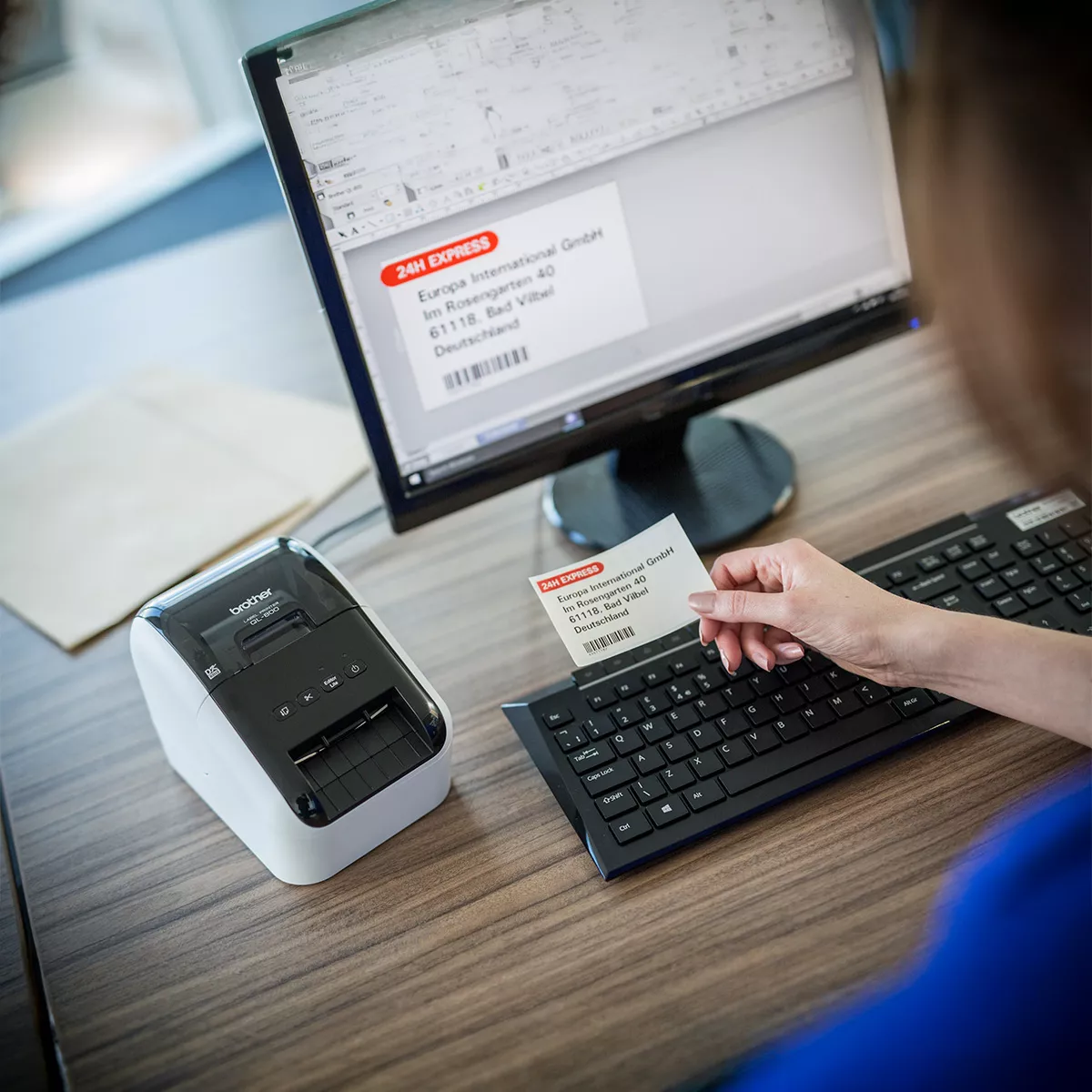 Persona utilizando una etiqueta impresa por la Brother QL-800 junto a una computadora
